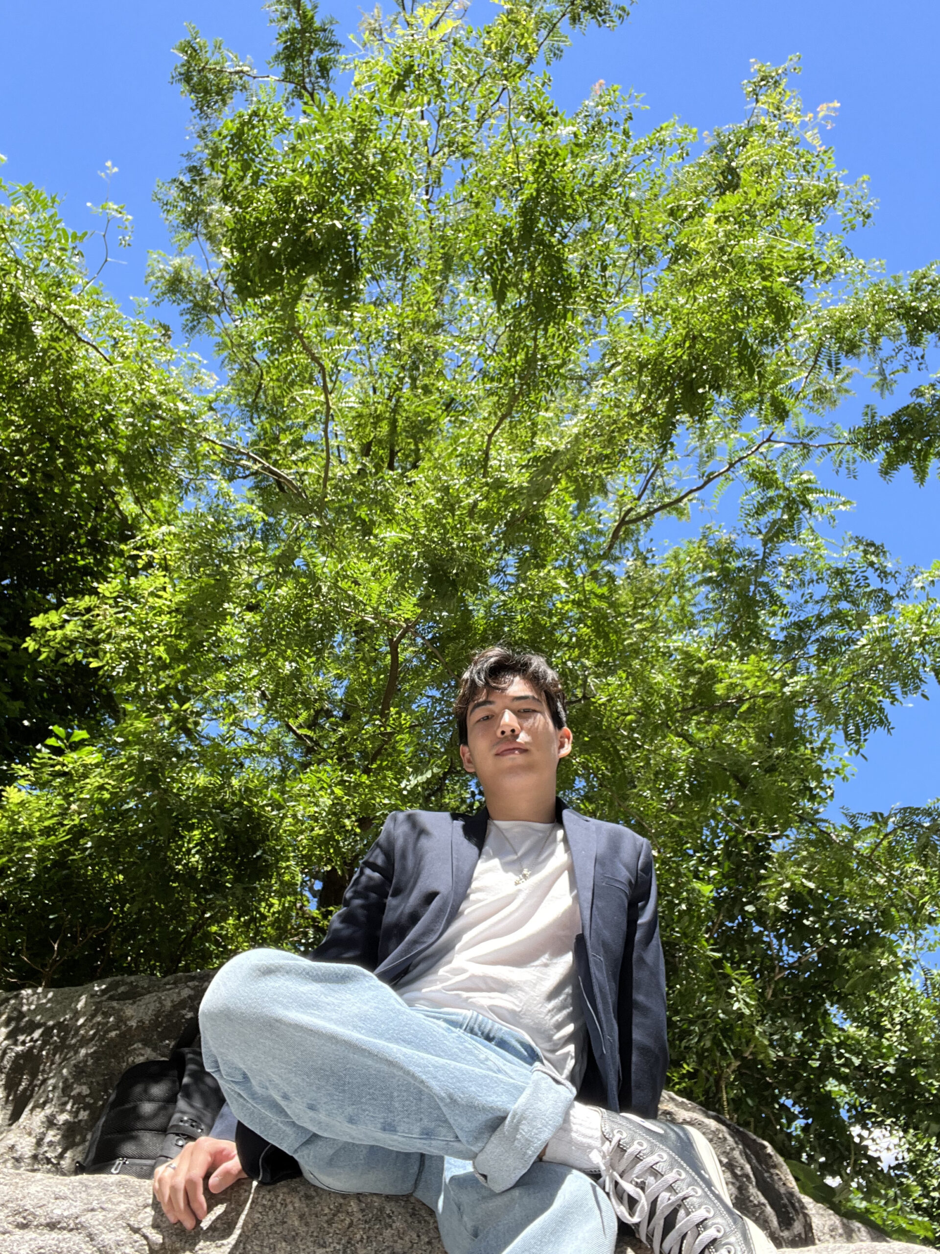 Nicholas Leung sitting by a tree in Brooklyn